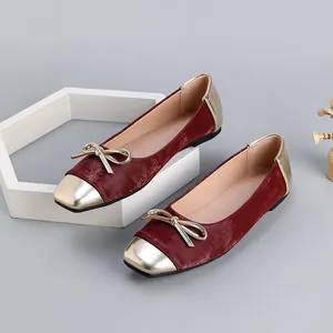 Close-up of elegant burgundy velvet ballet flats with gold square toe and bow detail