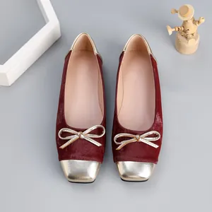 Elegant burgundy velvet ballet flats featuring metallic bow details and golden square toe caps