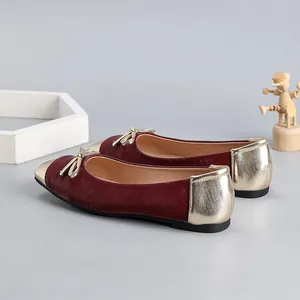 Detailed side view of burgundy velvet ballet flats with gold toe and bow accent.