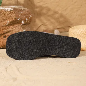 Detailed macro view of black anti-slip rubber sole of women's flip-flops on beach sand