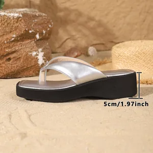 Side view of silver platform flip-flops showing 5cm heel height on a sandy beach