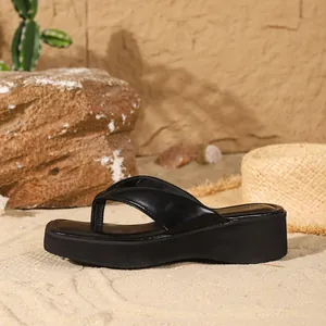 Detailed side view of black thick sole flip-flops with square toe design on beach sand