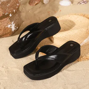 Close-up detail of black platform thong sandals featuring a modern square toe design