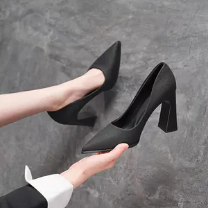 Macro view of black textured leather pointed-toe pumps with flared block thick heels