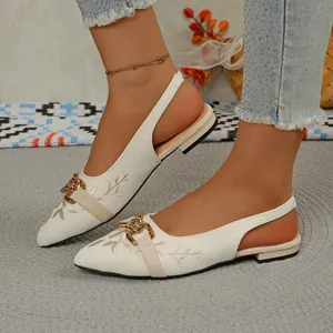 Close-up view of cream embroidered slingback sandals featuring a stylish gold chain buckle