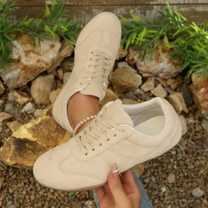 Λεπτομερής προβολή μπεζ καθημερινών sneakers με σχέδιο με κορδόνια και υφή σουέτ.