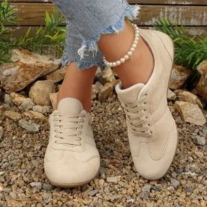 Κοντινό πλάνο από μπεζ σουέτ casual φλατ sneakers φορεμένα με τζίν παντελόνι