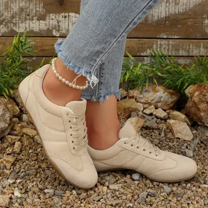 Κοντινό πλάνο μπεζ σουέτ αθλητικά παπούτσια με κορδόνια για γυναίκες σε πέτρες