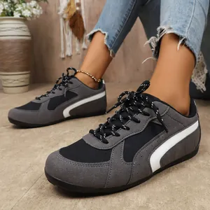 Gros plan de baskets grises et noires en patchwork avec détails de bandes blanches.