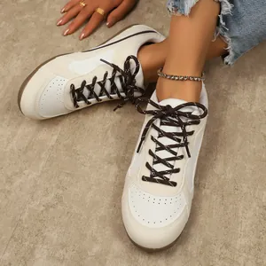 Gros plan de baskets de style GAT beige et blanc avec lacets marron pour femme.