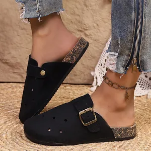 Close-up of black retro closed-toe mules with buckle strap and cork pattern sole