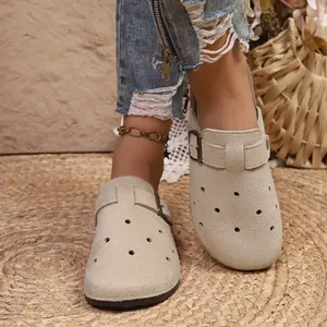 Macro view of beige suede platform clogs with adjustable buckle and perforated details