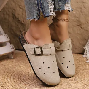 Beige suede-like clogs with metal buckle and perforations worn by model