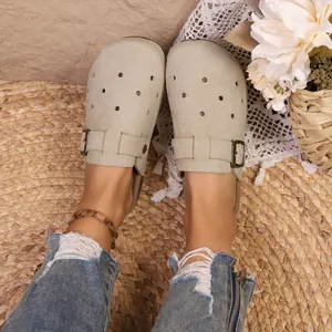 Close-up of women's beige Birkenstock-style clogs with buckle strap and hollow design