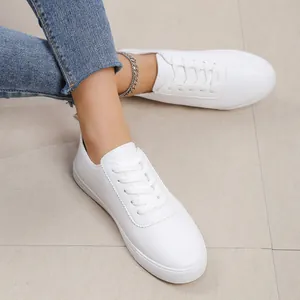 Λεπτομερής κοντινή λήψη λευκών γυναικείων sneakers με κορδόνια σε πλακάκια.