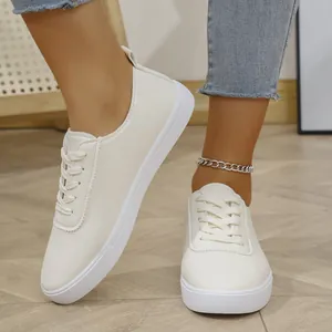 Κοντινό πλάνο λευκών γυναικείων casual sneakers με κομψά κορδόνια και επίπεδη σόλα