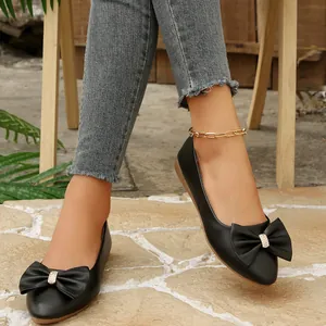 Elegant black pointed-toe ballet flats featuring a large bow and sparkling rhinestone buckle