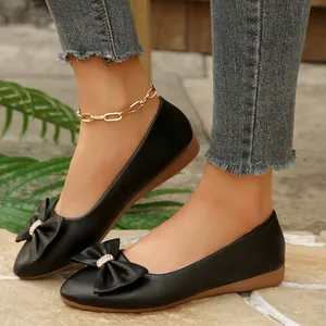 Close-up of black ballet flats with rhinestone bow detail on model's feet