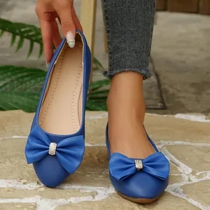 Close-up detail of women's blue flat shoes with rhinestone-studded bow decoration