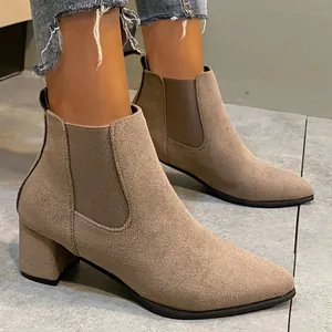 Close-up detail of stylish taupe suede Chelsea boots featuring chunky mid-heels and elastic panels