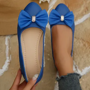Detailed view of blue pointed-toe flat shoes featuring a large decorative bow