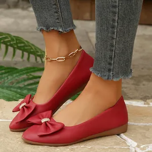 Close-up detail of red pointed-toe flats with decorative bow and crystal accents on feet