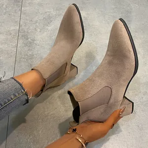 Macro view of suede Chelsea boots showing the block heel and elegant pointed toe design
