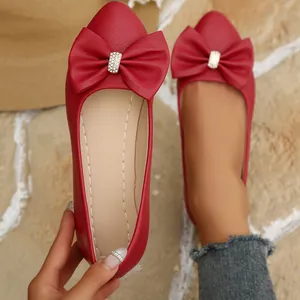 Detailed macro view of red pointed toe ballet flats featuring elegant bow with rhinestone