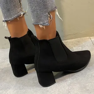 Close-up side view of fashionable black suede chunky heel Chelsea boots worn with jeans