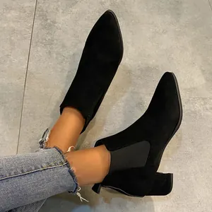 On-foot view of black suede pointed toe Chelsea boots with chunky heels and frayed jeans