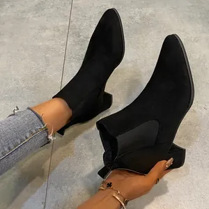 Detailed view of stylish black suede pointed-toe Chelsea boots featuring a chunky block heel.
