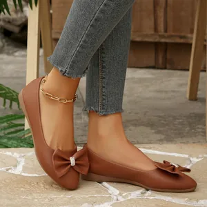 Close-up of brown pointed toe ballet flats with elegant bow knot and rhinestone details