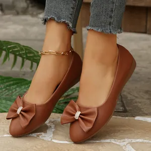 Detailed view of brown pointed-toe flats featuring a large bow and rhinestone accent.
