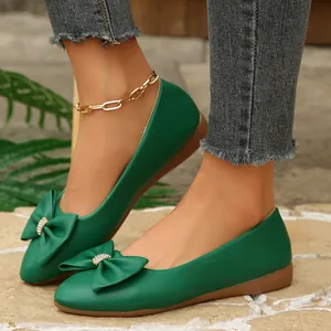 Close-up of elegant green ballet flats with rhinestone bow detail and gold chain anklet