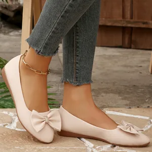 Detailed macro shot of beige ballet flats featuring an elegant bow with a rhinestone cluster