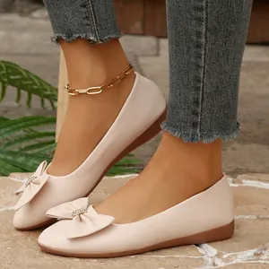 Detailed shot of beige pointed-toe flat shoes with an elegant bow accent