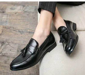 Detalle de elegantes mocasines de cuero negro para hombre con borlas usados en estilo casual