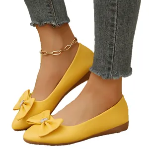 Women's bright yellow pointed toe slip-on flats with oversized bow and sparkle detail.