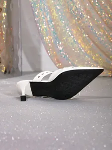 Vue détaillée de mules blanches à talons hauts avec semelle noire et doubles lanières.
