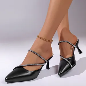 Detailansicht von eleganten schwarzen spitzen Stiletto-Mules mit Strassriemen am Modell
