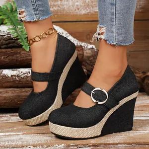Close-up of stylish women's denim wedge pumps featuring a buckle strap and woven platform