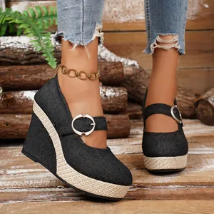 Close-up of black denim wedge shoes with round buckle and woven espadrille sole