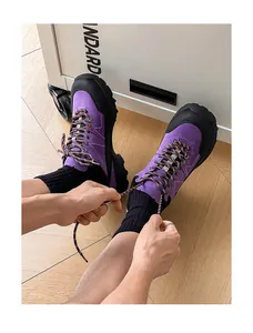 Macro detail view of purple hiking shoes with person tying laces on wooden floor