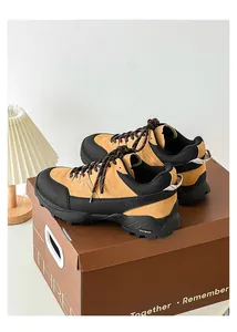 Detailed view of tan and black hiking sneakers placed on a brown shoebox in a studio set