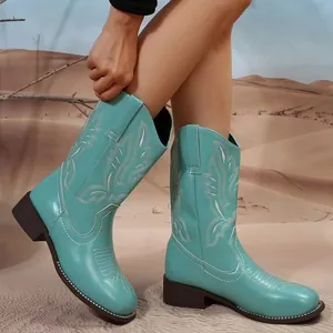 Vue détaillée de bottes de cowboy brodées turquoise pour femmes dans le désert