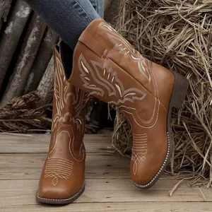 Gros plan sur des bottes de cow-boy marron brodées pour femmes avec talons épais.