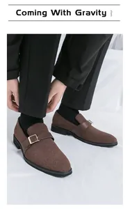 Primo piano di mocassini marroni con fibbia indossati con pantaloni neri su bianco
