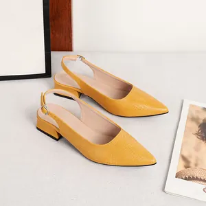 Dettaglio di scarpe slingback gialle a punta con trama a pelle di serpente e tacco