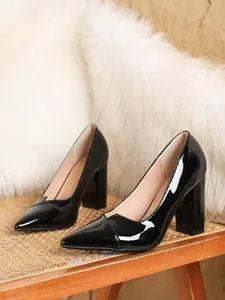 Elegante schwarze Lackleder Pumps mit spitzer Kappe und Blockabsatz auf Stuhl