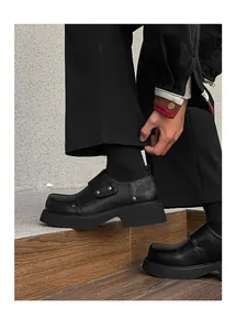 Detailed view of men's black chunky platform dress shoes featuring metal rivet accents
